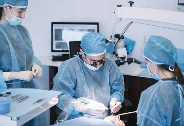 Medic stomatolog si asistentii executa o extractie