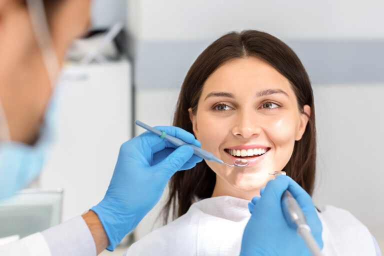 Femeie drăguță zâmbitoare care se uită cu încredere la medicul dentist în timpul tratamentului